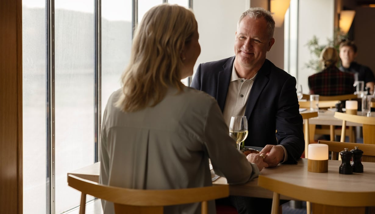 To personer som sitter ved et bord i en restaurant og holder hender.