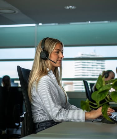 Person jobber ved skrivebord med datamaskin og hodetelefoner