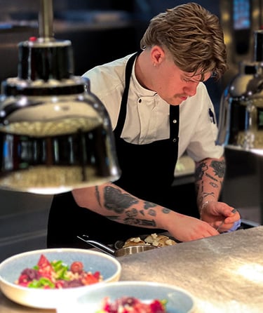 En kokk som forbereder mat på et profesjonelt kjøkken.