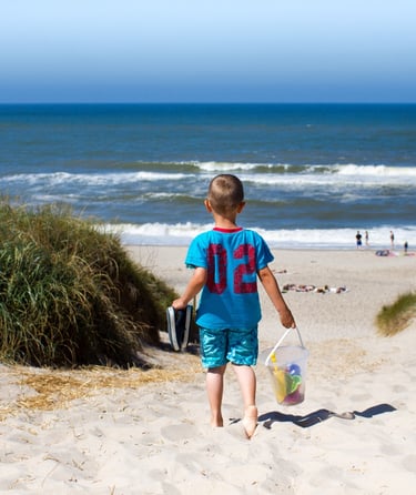 Barn som går ned en sandsti mot stranden.