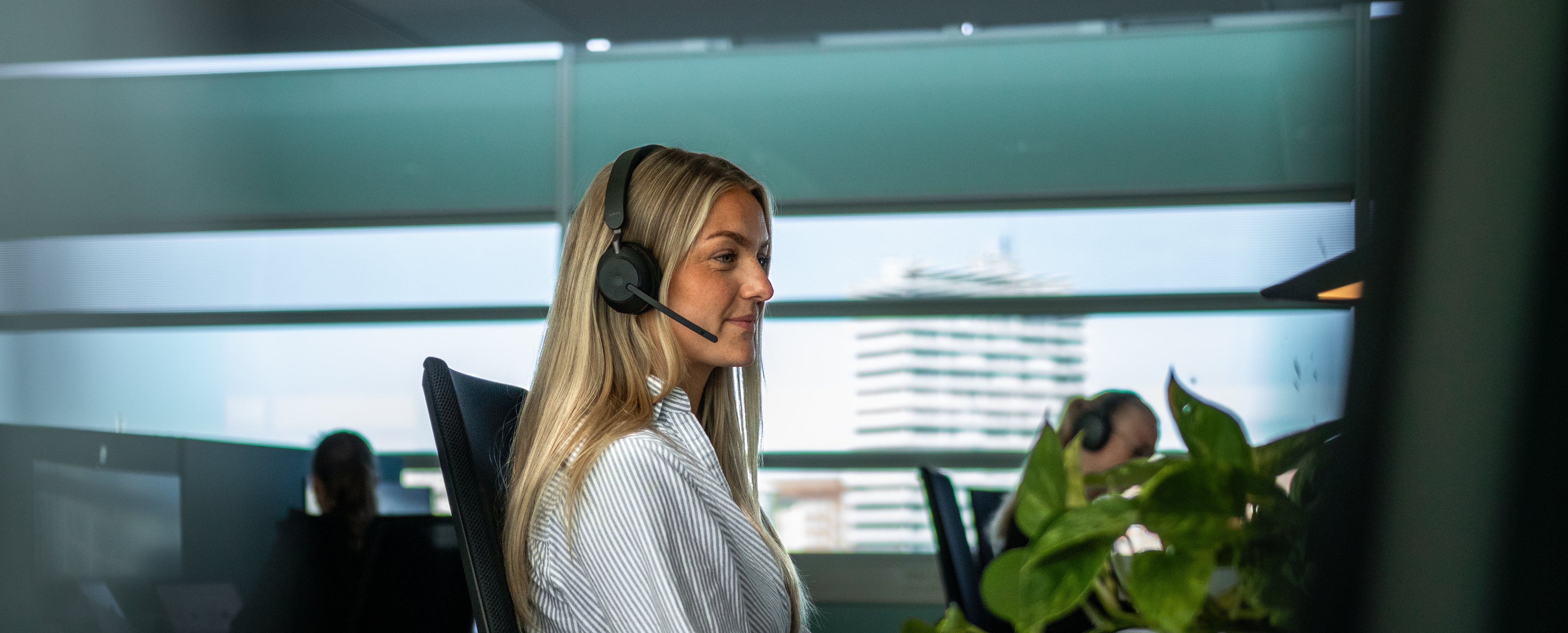 Person jobber ved skrivebord med datamaskin og hodetelefoner