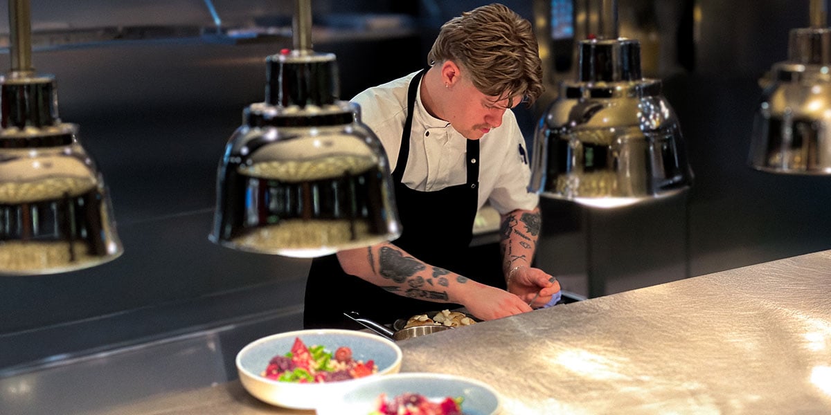 En kokk som forbereder mat på et profesjonelt kjøkken.