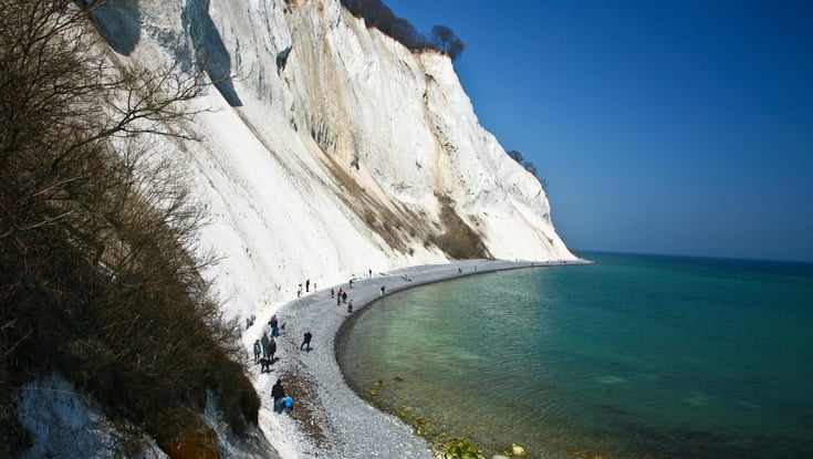 Kystlandskap med hvite kalkklipper og steinstrand.