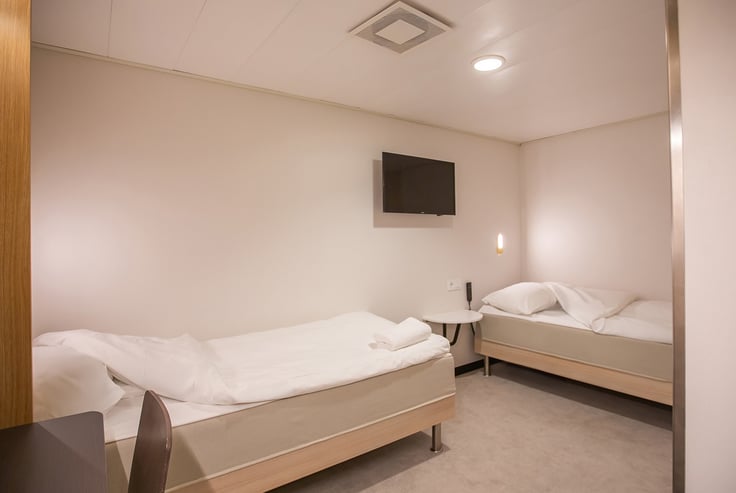 Tilgjengelig lugar med to enkeltsenger og et rundt bord.