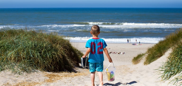 Barn som går ned en sandsti mot stranden.