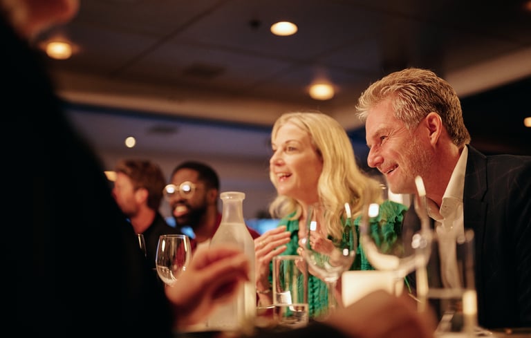 Venner samlet rundt et restaurantbord med vin og vann, og nyter en koselig kveld inne