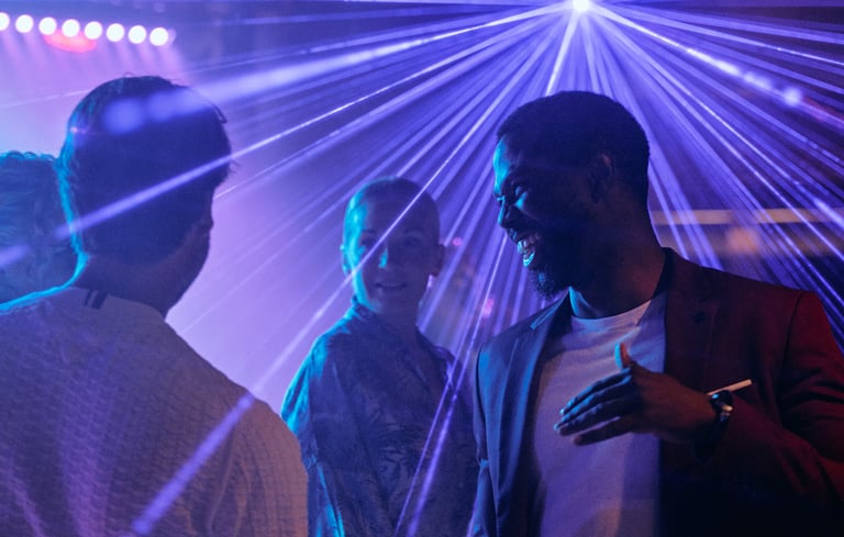 Gruppe mennesker som snakker på fest med fargerik belysning.