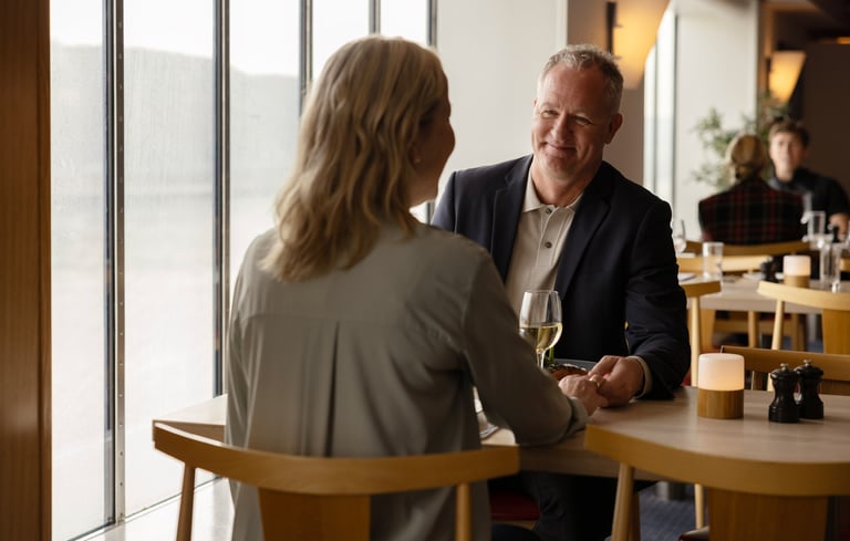 To personer som sitter ved et bord i en restaurant og holder hender.