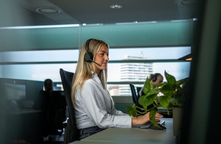 Person jobber ved skrivebord med datamaskin og hodetelefoner